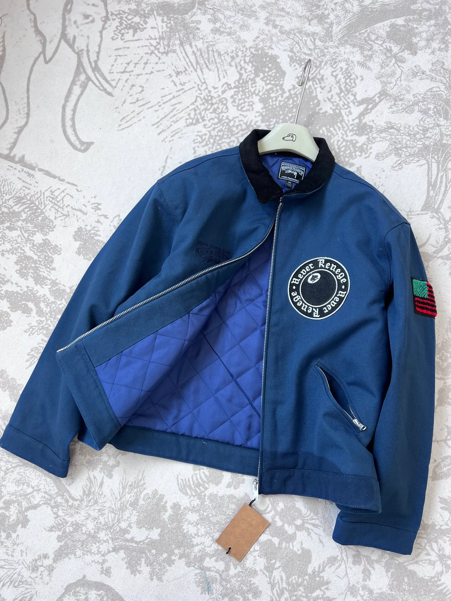 New T66# jacket version 340💰/quilted version 360💰 Stussy x Denim Tears joint model SS25 round chest logo printed zipper opening work jacket, same style for men and women, navy blue Accessories: original dismantling and development, one-to-one customized small labels, collar labels, washing, hang tags, hardware, etc. - Fabric: It is made of the original one-to-one 275g pure cotton fabric, and the high-count double yarn process improves softness and durability. The whole piece is washed, giving it a vintage navy blue distressed texture, echoing the nostalgic tone of the campus theme.   - The collar part is spliced ​​with corduroy or cotton fabrics, which contrasts with the washed cotton of the main body to enhance the visual layering and improve wearing comfort.    - The iconic "Double S + Kapok Ring" combination logo on the back is three-dimensional embroidery. The cotton texture and letter lines stand out in three-dimensionality, enhancing brand recognition.   - A small area of ​​embroidery, card colors and Never Renege slogans are added to the side to echo the cultural theme of the African American community.   - Continuing the short and wide cut of the Detroit work jacket, the cuffs and hem are tightened to give both functionality and practicality.   - The interior adopts quilting technology to provide moderate warmth while maintaining lightness, which is suitable for spring when the temperature difference between morning and evening is large.     - Equipped with YKK metal zipper, it opens and closes smoothly and is durable, and the edge wrapping process improves the overall structural strength.  - African cultural elements: symbols such as the Ace of Spades, the Bid Whist card game scene, and the Jamaican high school area code "718" are integrated into the single product through embroidery, printing and other processes to convey the cultural proposition of Denim Tears.  - Joint logo: Stussy double S logo and Denim Tears kapok ring are combined with embroidery and printing to strengthen the uniqueness of the joint series.  Size: M-2XL M bust 127 length 65.5 sleeve length 61 shoulder width 53.3 [160-165cm 60-70kg] L bust 132 length 66.8 sleeve length 62.2 shoulder width 55.9 [165-170cm 70-85kg] 【170-175cm 80-95kg】 XXL Bust 142.2 Clothes Length 69.3 Sleeve Length 64.8 Shoulder Width 61 【175-180cm 90-105kg】
